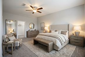Houston apartment for rent - A bedroom with a large bed, a chair, and a dresser.