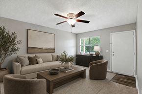 Mooresville apartment for rent - A living room with a beige couch, a brown armchair, a coffee table, and a ceiling fan.
