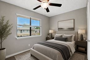 Mooresville apartment for rent - A bedroom with a large bed, a ceiling fan, and a window with blinds.