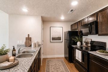 Layton apartment for rent - A kitchen with a black refrigerator and wooden cabinets.