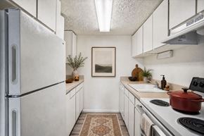 Layton apartment for rent - A kitchen with a refrigerator, stove, and a rug on the floor at The Morgan Apartments, Layton, Utah