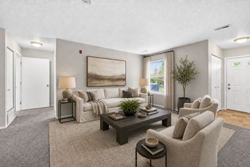 Saginaw apartment for rent - A living room with a grey carpet and a large painting on the wall.