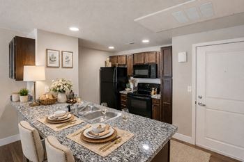 Kitchen with granite breakfast bar and black appliances