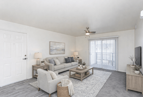 Heber City townhouse for rent - A living room with a grey couch, a white door, a ceiling fan, and a television.