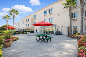 Huntington Beach apartment for rent - A sunny day at the outdoor seating area of a building with tables and chairs.