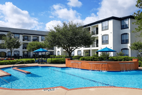 Katy apartment for rent - A swimming pool in front of a white apartment building.