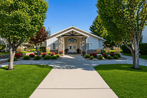 Brigham City apartment for rent - A house with a stone facade is surrounded by a well-kept lawn and trees.