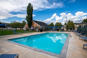 Heber City townhouse for rent - A large outdoor swimming pool surrounded by a fence and lounge chairs.