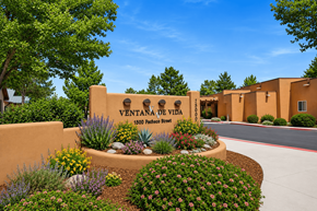 Sante Fe apartment for rent - The image shows a beautifully landscaped entrance to Ventana de Vida with a clear blue sky above.