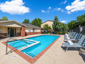 Logan apartment for rent - A swimming pool surrounded by lounge chairs and a building in the background.