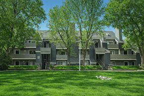 Arvada apartment for rent - A large house with a grey exterior and a green lawn in front.