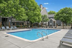 Arvada apartment for rent - A swimming pool surrounded by trees and lounge chairs.
