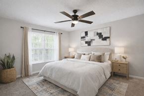 Stone Mountain apartment for rent - A bedroom with a large bed, a ceiling fan, and a plant.
