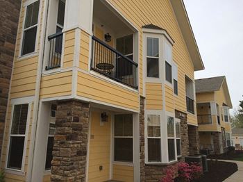 A yellow house with a porch and a balcony