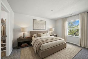 Lansing apartment for rent - A bedroom with a large bed and a window overlooking trees.