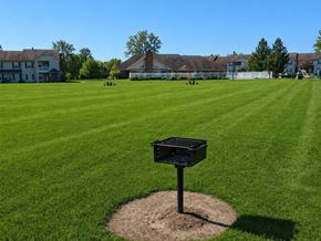 Lansing apartment for rent - A black trash bin sits on a mound of dirt in the middle of a grassy field.