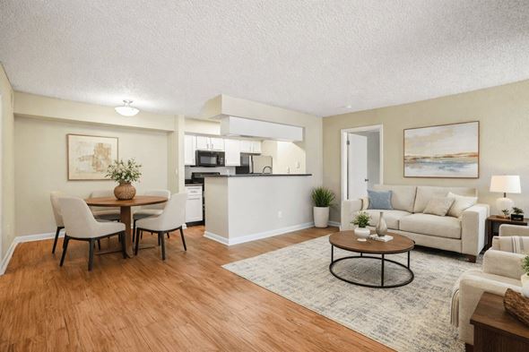 Greeley apartment for rent - A living room with a white couch and a dining table with chairs.