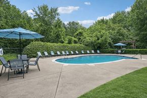 Charlotte apartment for rent - A pool surrounded by lawn chairs and umbrellas.