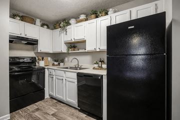 Charlotte apartment for rent - A black refrigerator stands in a kitchen with white cabinets and a black stove.