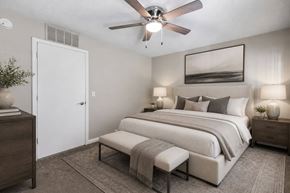 Shelby apartment for rent - A bedroom with a large bed, a bench, and a ceiling fan.