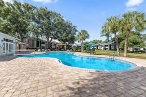 Daytona Beach apartment for rent - A swimming pool surrounded by a brick patio and palm trees. at Epic Apartments , Florida, 32114