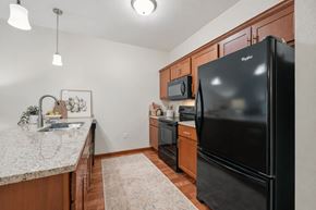 Andover apartment for rent - A kitchen with a black refrigerator and wooden cabinets.