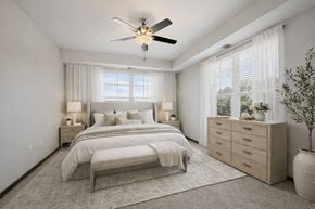 Maple Grove apartment for rent - A bedroom with a large bed, a ceiling fan, and a window with blinds.