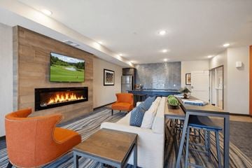 Maple Grove apartment for rent - A modern living room with a fireplace and a television displaying a golf course.