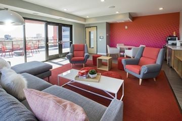 Minneapolis apartment for rent - A living room with a grey couch and red chairs.