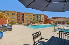 Rio Rancho apartment for rent - A pool area with a table and chairs and a building in the background.