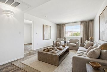 Rio Rancho apartment for rent - A modern living room with a grey sofa, a wooden coffee table, and a large painting on the wall.