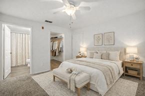 Sanford apartment for rent - A bedroom with a large bed, a bench, and a ceiling fan.