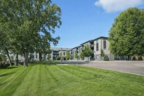 Vadnais Heights apartment for rent - A grassy area in front of a building with trees on the sides at Aster Meadow, Vadnais Heights, MN, 55127