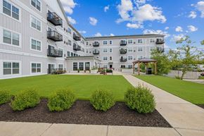 Falcon Heights apartment for rent - A large building with a white exterior and a courtyard with bushes and a gazebo.