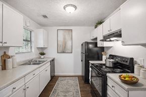 College Park townhouse for rent - A kitchen with white cabinets and a black stove top oven.