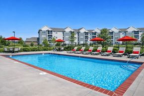 St Cloud apartment for rent - A swimming pool with red umbrellas and apartment buildings in the background.