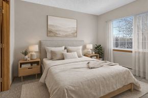 St Cloud apartment for rent - A bedroom with a large bed, a nightstand with a lamp, and a painting on the wall.