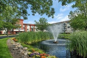 St Cloud apartment for rent - A fountain in the middle of a pond surrounded by grass and flowers.