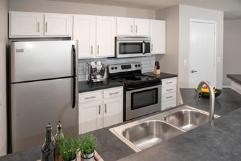 A modern kitchen with a stainless steel refrigerator, microwave, oven, and sink.