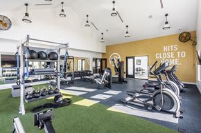Kansas City apartment for rent - A gym with a green floor and a yellow wall that says "Hits Close to Home.".