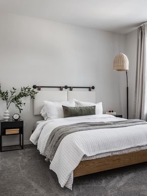 Kansas City apartment for rent - A bedroom with a large bed and a nightstand with a plant on it.
