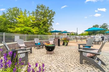 An outdoor patio with tables chairs and umbrellas and a fire pit