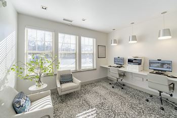 An office with three computers and a chair and a window