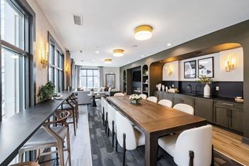 A dining room with a long wooden table and white chairs