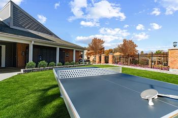 Outdoor ping pong table with building in background  