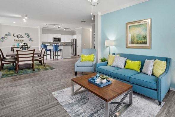 Tampa apartment for rent - A living room with a blue couch and a coffee table at The Grand Reserve at Tampa Palms Apartments, Florida