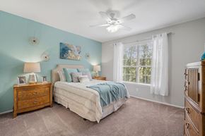 Tampa apartment for rent - A bedroom with a bed, dresser, and ceiling fan at The Grand Reserve at Tampa Palms Apartments, Tampa, FL