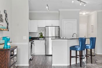 A kitchen with a refrigerator, sink, and two blue barstools.