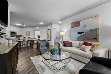 Charlotte apartment for rent - A modern living room with a white sofa, a glass coffee table, and a large abstract painting on the wall.