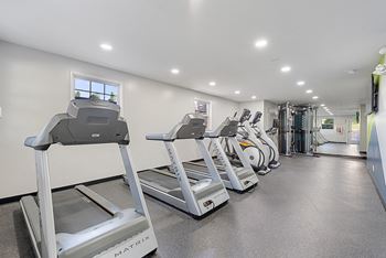 A row of treadmills in a gym with cardio equipment